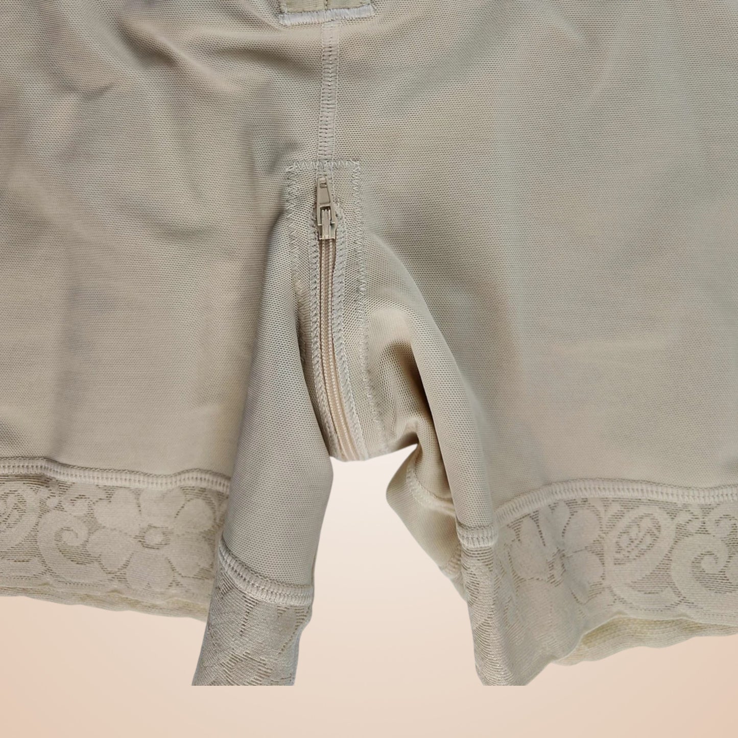 Gaine ventre plat nude avec fermeture éclair et bordure en dentelle fine.