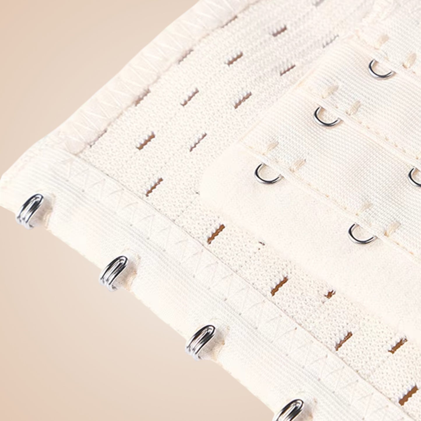 Détail du bustier corset blanc avec crochets métalliques et couture fine en tissu texturé.