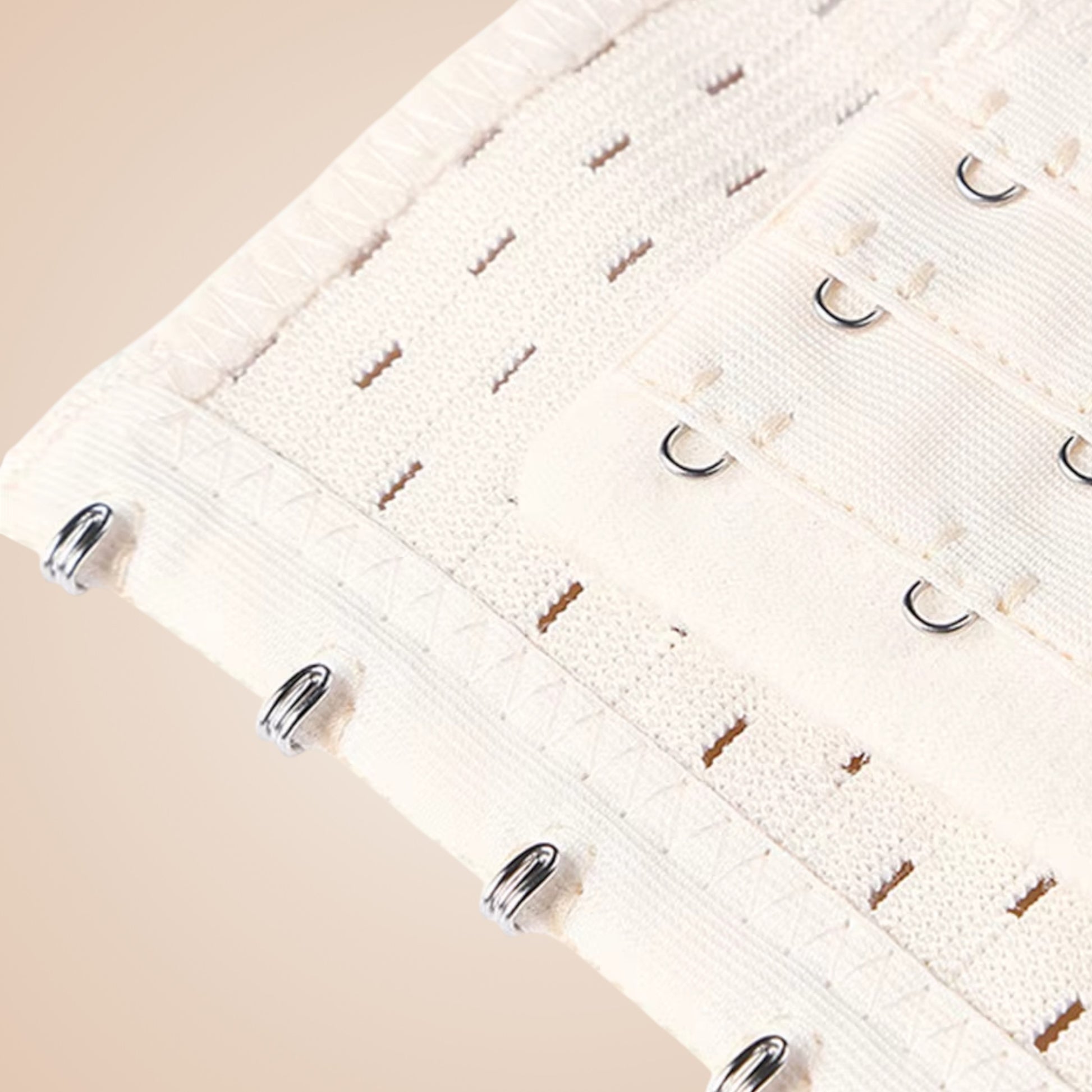 Détail du bustier corset blanc avec crochets métalliques et couture fine en tissu texturé.